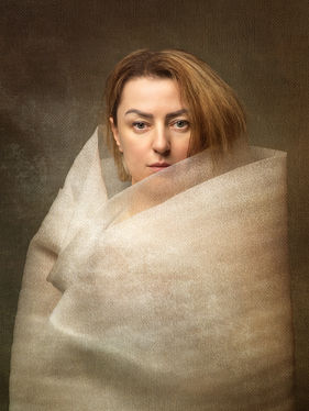 Portrait of a woman with translucent fabric wrapped closely around the upper body, showing reduced movement and restrained expression.