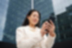 A woman in a city looking ather brokerage account on her phone