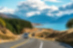 Camper van driving down a road by a lake