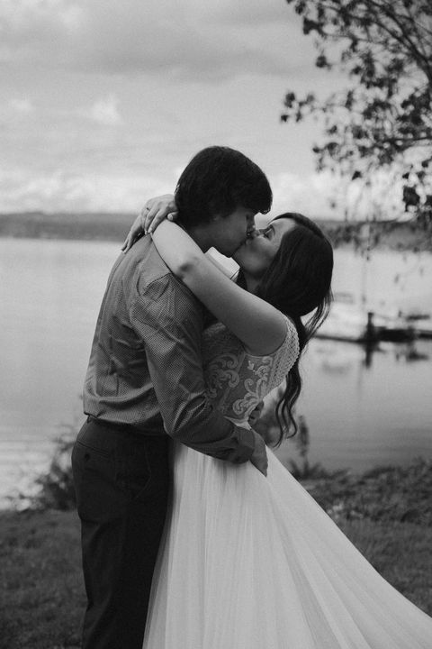 Romantic couple kissing by lake, wedding photo