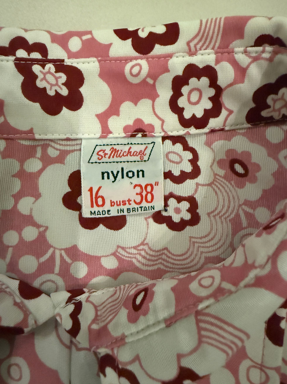 Thumbnail: pink white and burgundy flower power print long sleeve ladies shirt from 1960s with long rounded collars. Label close up