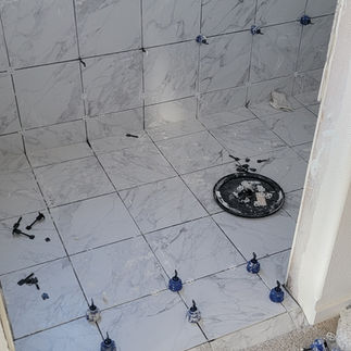Craftsmen at work, carefully positioning tiles to create a seamless and stylish finish for the accessible shower.
