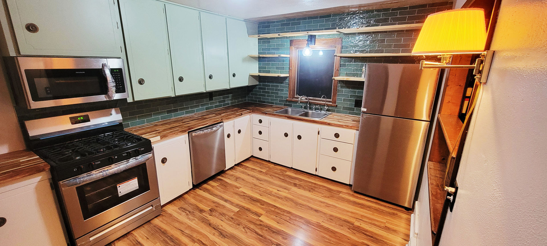 Kitchen renovation showcasing butcher block countertops, repainted cabinets, new appliances, and flooring.