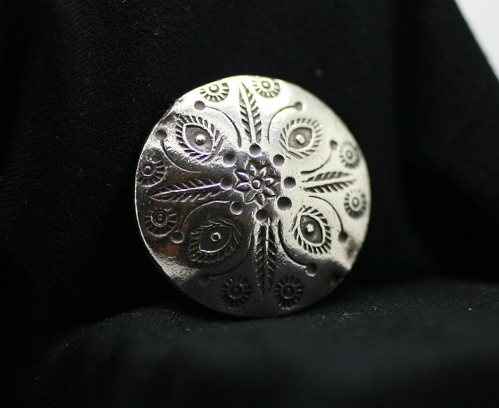 Fine silver circular bead with exotic flower patterns grooved into the smooth surface