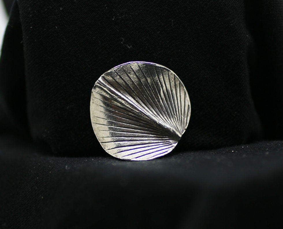 Thai silver circular spiraling bead with a central ridge and peacock-like groove patterns