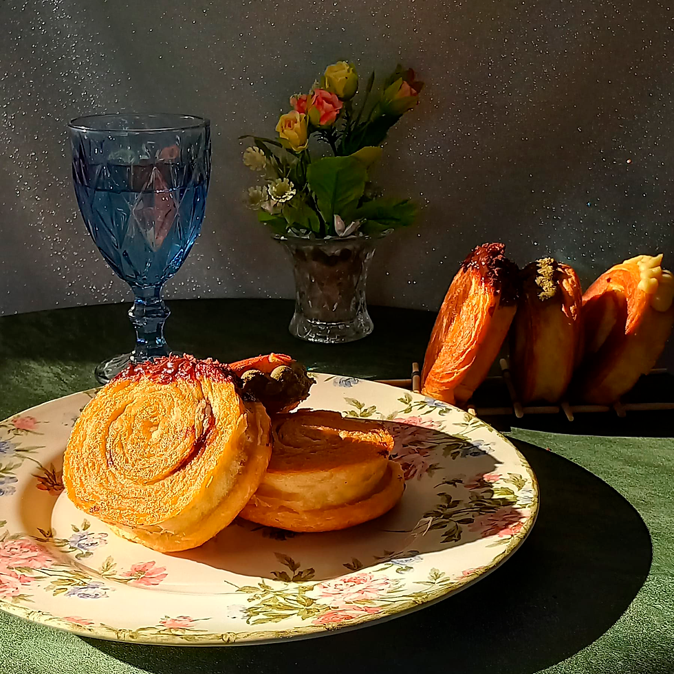 Em cima de uma mesa possui três pedaços de croissant doce, com recheios de cacau, matcha e baunilha