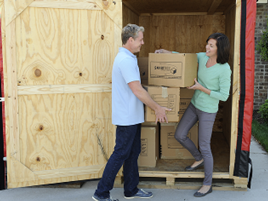 Couple loading boxes into a wooden storage container