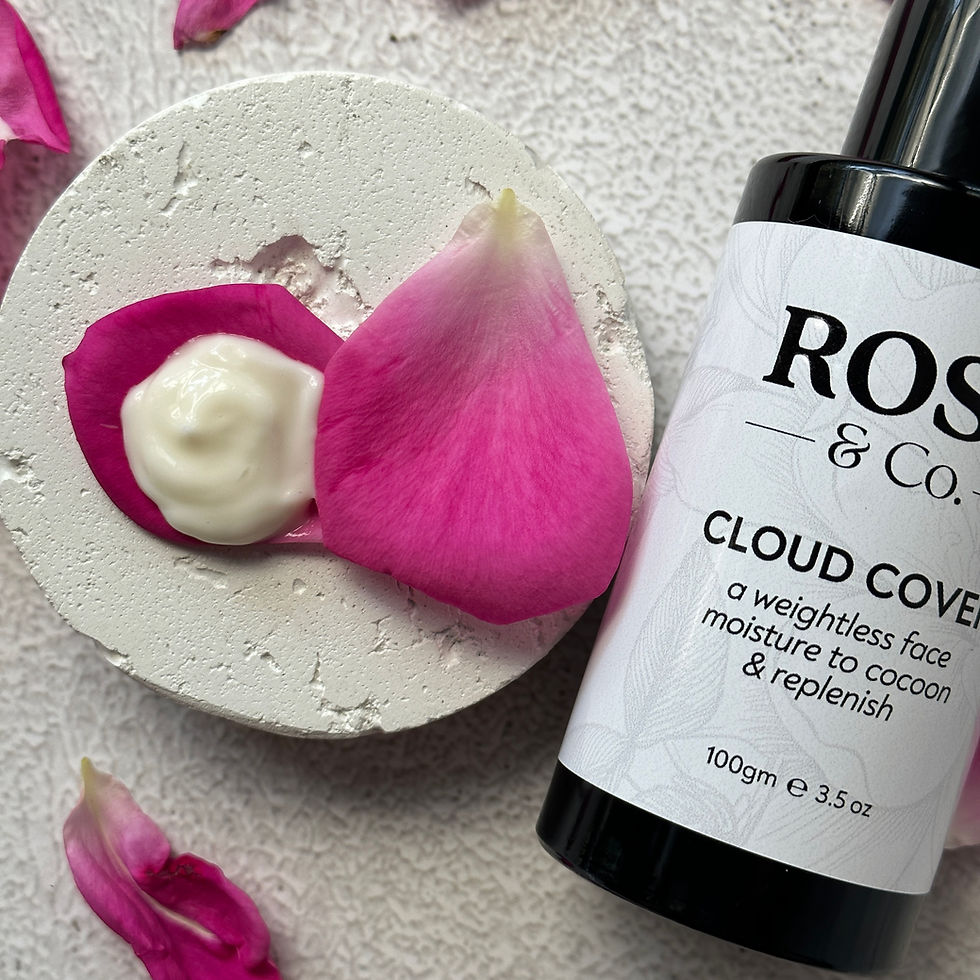A black glass bottle of face cream sourrounded by pink rose petals