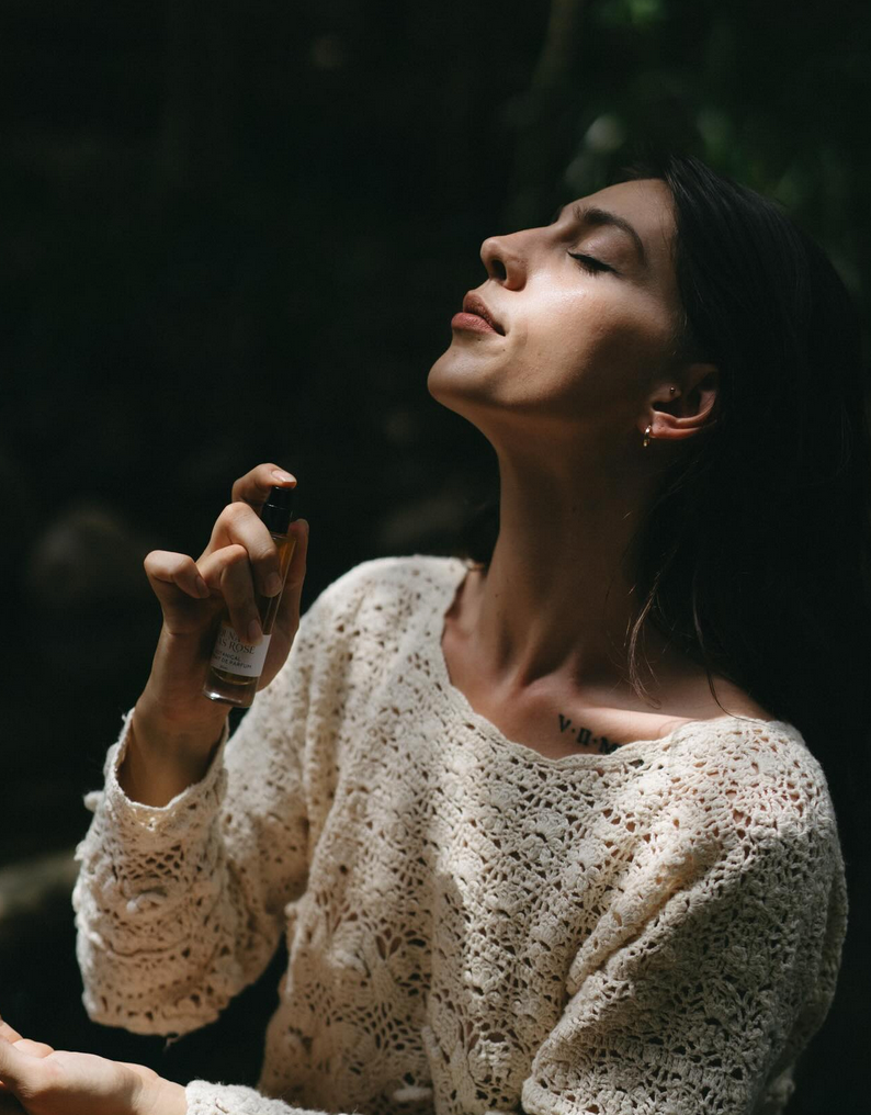 A woman sraying natural perfume in a nature setting