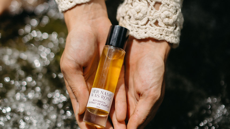 A woman gently cups a bottle of Rose and Co. natural perfume in her hands in a natural setting