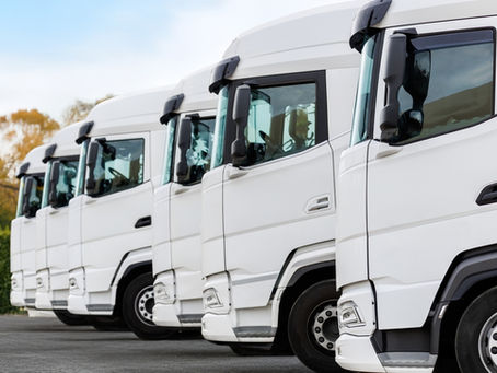 Alignement de camions utilitaires blancs destinés au transport professionnel, illustrant le financement de véhicules pour entreprises et artisans.