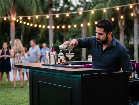 Bartender sirviendo un cóctel en una barra móvil negra durante una fiesta en el patio en Orlando, Florida