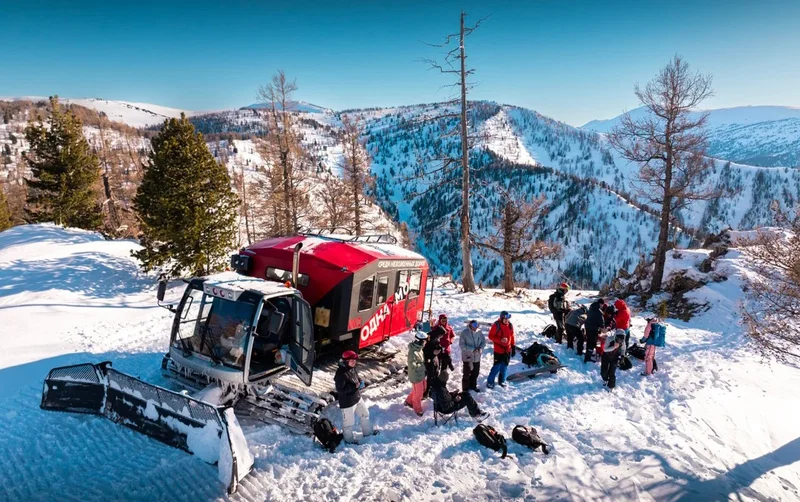 Snowcat rouge sur une crête entre les mélèzes, Altaï, Kazakhstan