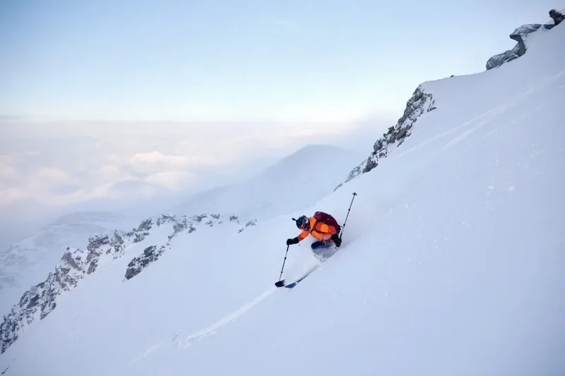 Skieur sous une corniche, mer de nuages en arrière-plan