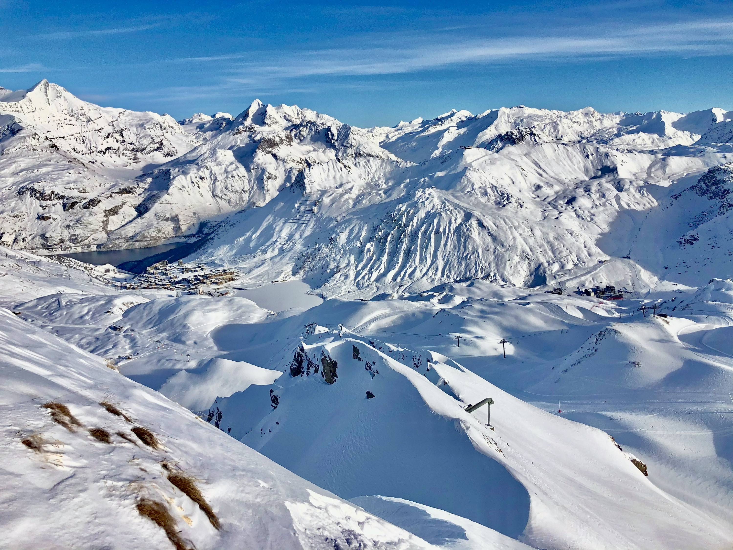 Tignes Pistenplan: Tignes le Lac am zugefrorenen See, umgeben von verschneiten Hängen und Liften des Skigebiets