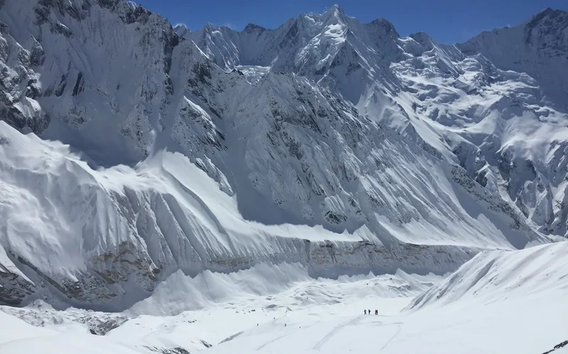 Gletscherwand der Annapurnas, winzige Skifahrer an ihrem Fuß
