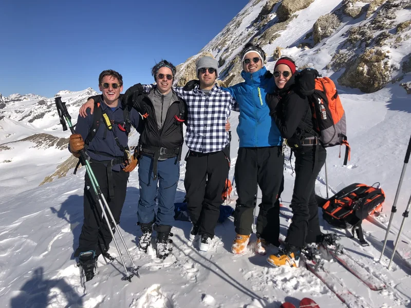 Groupe de cinq amis sur une crête, skis aux pieds