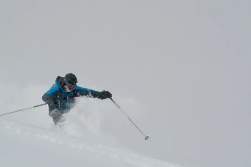 Ein Skifahrer in blauer Jacke im Pulverschnee