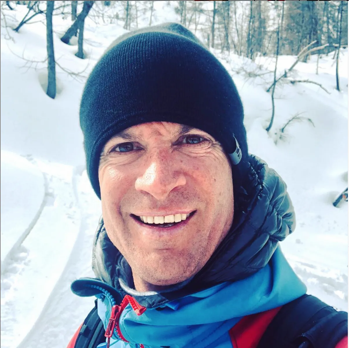 Boris Malesset, founder of PowderWeGo, smiling in a beanie in a snowy forest
