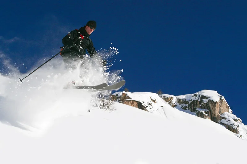 Skieur en plein saut dans la poudreuse, ciel bleu profond