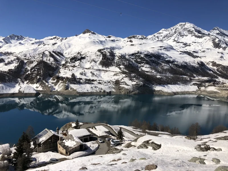 Lac de barrage en miroir et sommets enneigés, ciel bleu