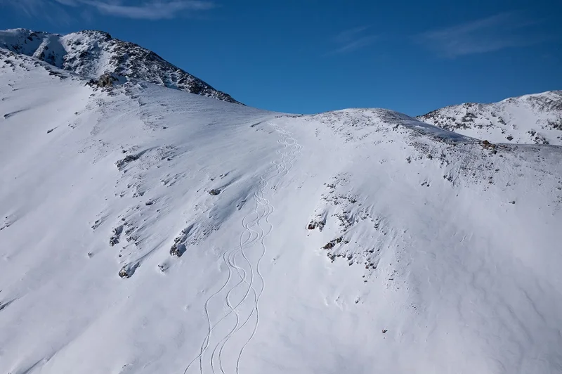 Hang im Altai, durchzogen von S-förmigen Spuren, tiefblauer Himmel