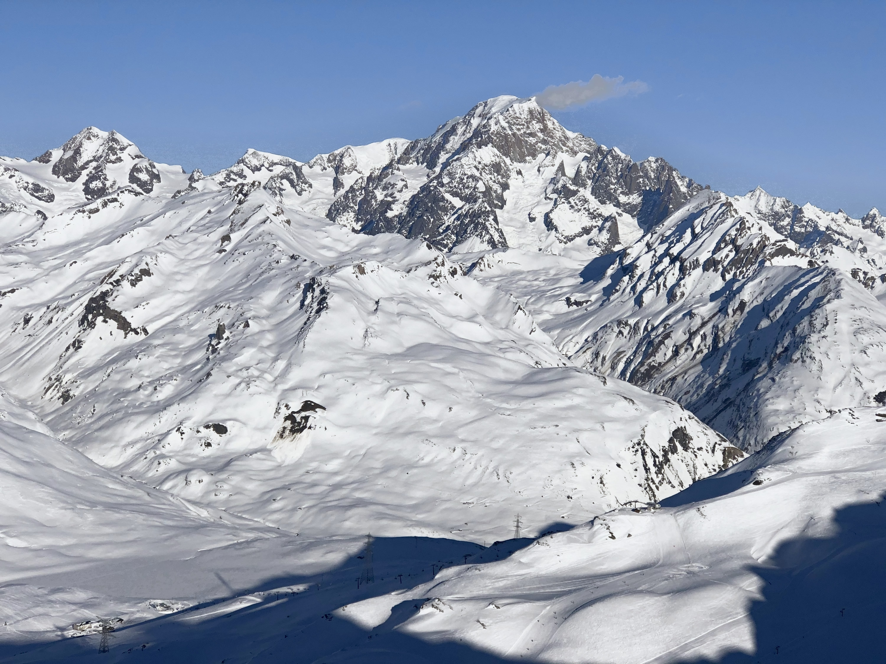 Heliskiing in den Alpen: großes vergletschertes Massiv über verschneiten Rücken und Tälern unter blauem Himmel