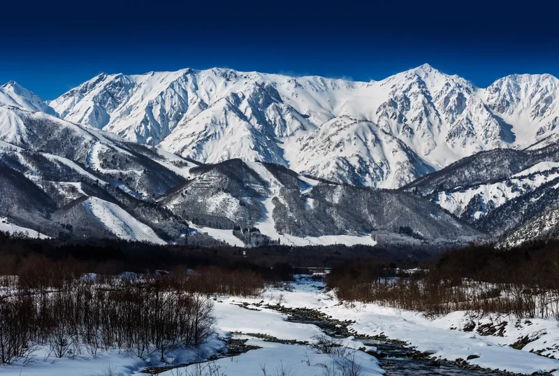 Verschneite Bergkette über einem Tal, Japan