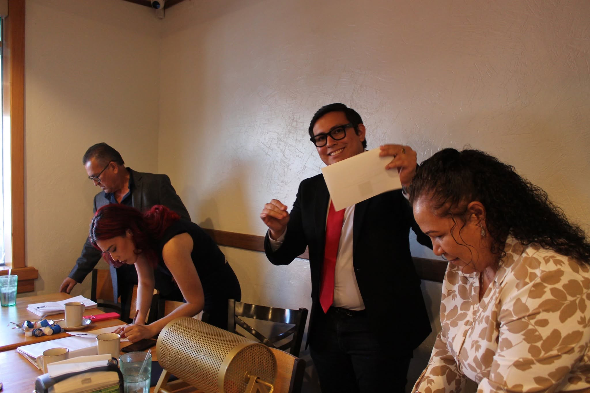 An EPHIADA association representative holding a raffle envelope during a gathering.