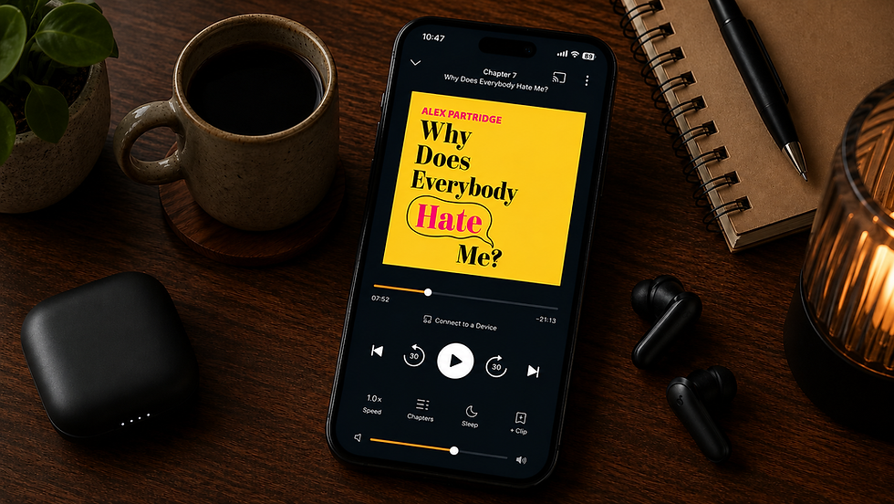 Image: A smartphone playing the audiobook Why Does Everybody Hate Me? sits on a wooden desk next to a cup of coffee, earbuds, and a notebook.