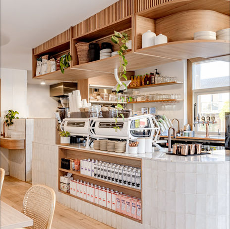 Stylish coffee bar interior featuring wooden shelving and multiple espresso machines.