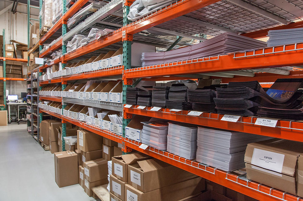Warehouse aisle with orange racks packed with labeled boxes and stacked paper sheets in an organized storage room