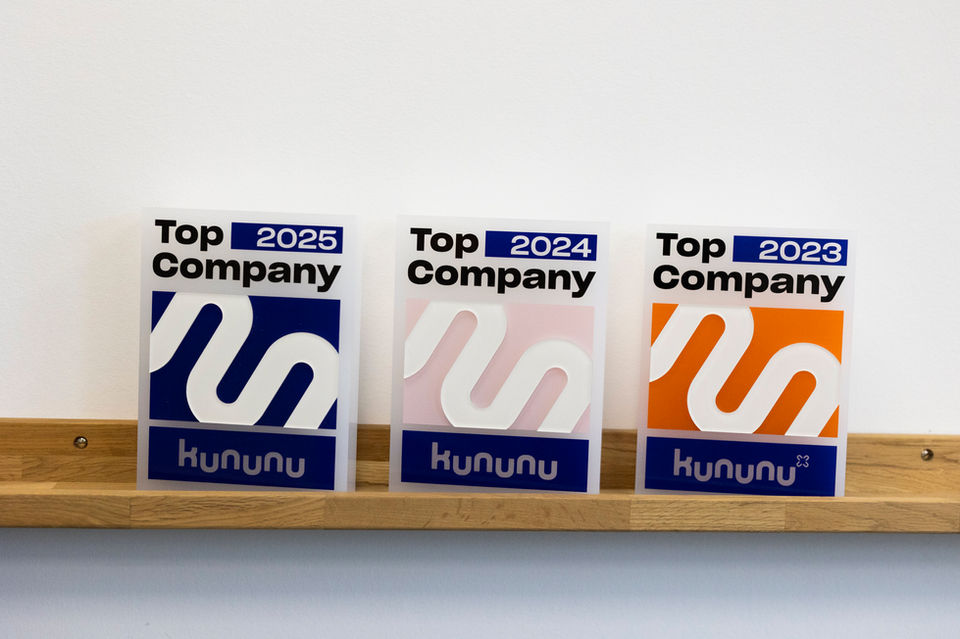 Das Foto zeigt drei Plexiglasaufsteller mit der Schrift Top Company 2025, Top Company 2024 und Top Company 2023