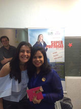 Two women smiling for a photo with "Speak Success" poster