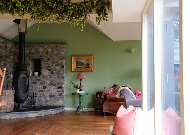 Interior of The Cow Shed living room, showing a cosy reading nook by the fireplace.  Designed by Rural Wildings Interior Design. 
