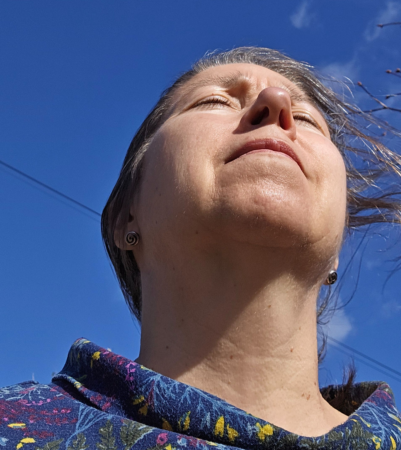 looking up at a person standing outside on a sunny day breathing in fresh air