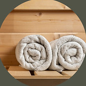 SAUNA zussamen two white towels rolled up on a sauna bench