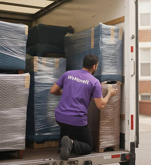 Déménageur WeMoveIt chargeant des meubles protégés dans un camion de transport.