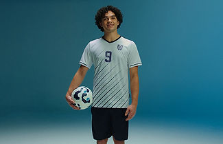 Boy standing in his soccer uniform holding a soccer ball