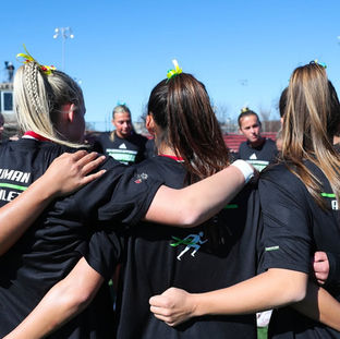 Girls lacrosse team standing in a huddle