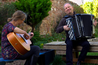 Catherine and Gordon playing in a garden on a bench.