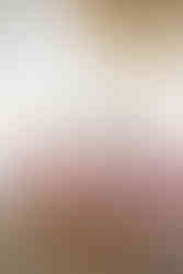 The bride and her bridesmaids are all sitting on the sofa in the middle of a brightly lit brides suite at the Selah Event Venue. The ladies are all in their silk knee-length robes and fluffy slippers. Image captured by Photography of Sarah Mae.