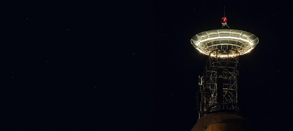 A landmark antenna atop a former telecom tower transcodes cosmic background radiation into words scrolling across surrounding displays, inviting citizens to look toward the stars and let their imagination wander.