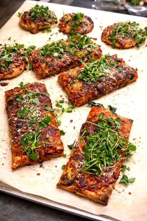 Savory flatbread appetizers with fresh herbs and greens.
