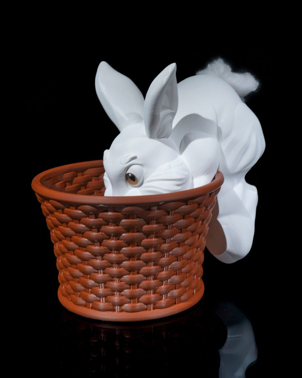 Thumbnail: White rabbit peeking into brown woven basket planter
