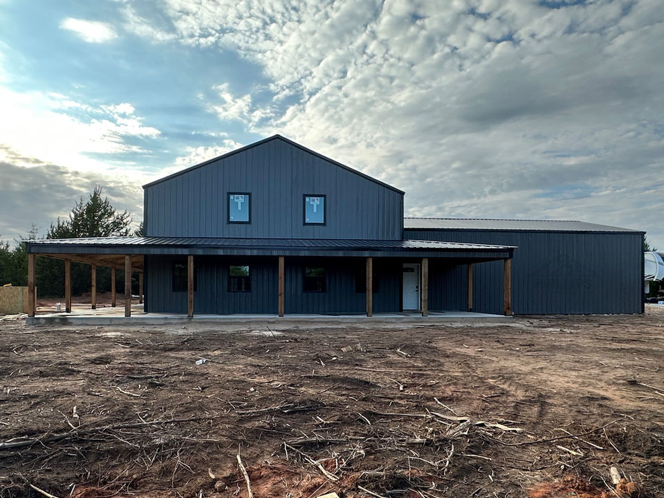 Modern all-black barndominium with wraparound porch