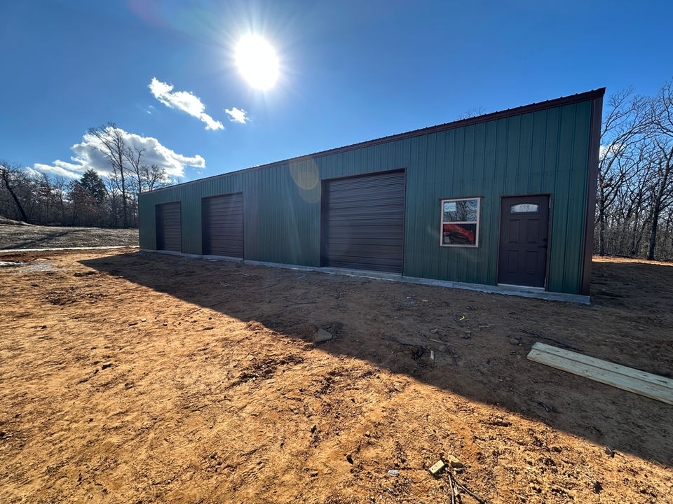 Green and black commercial shop with three overhead garage doors