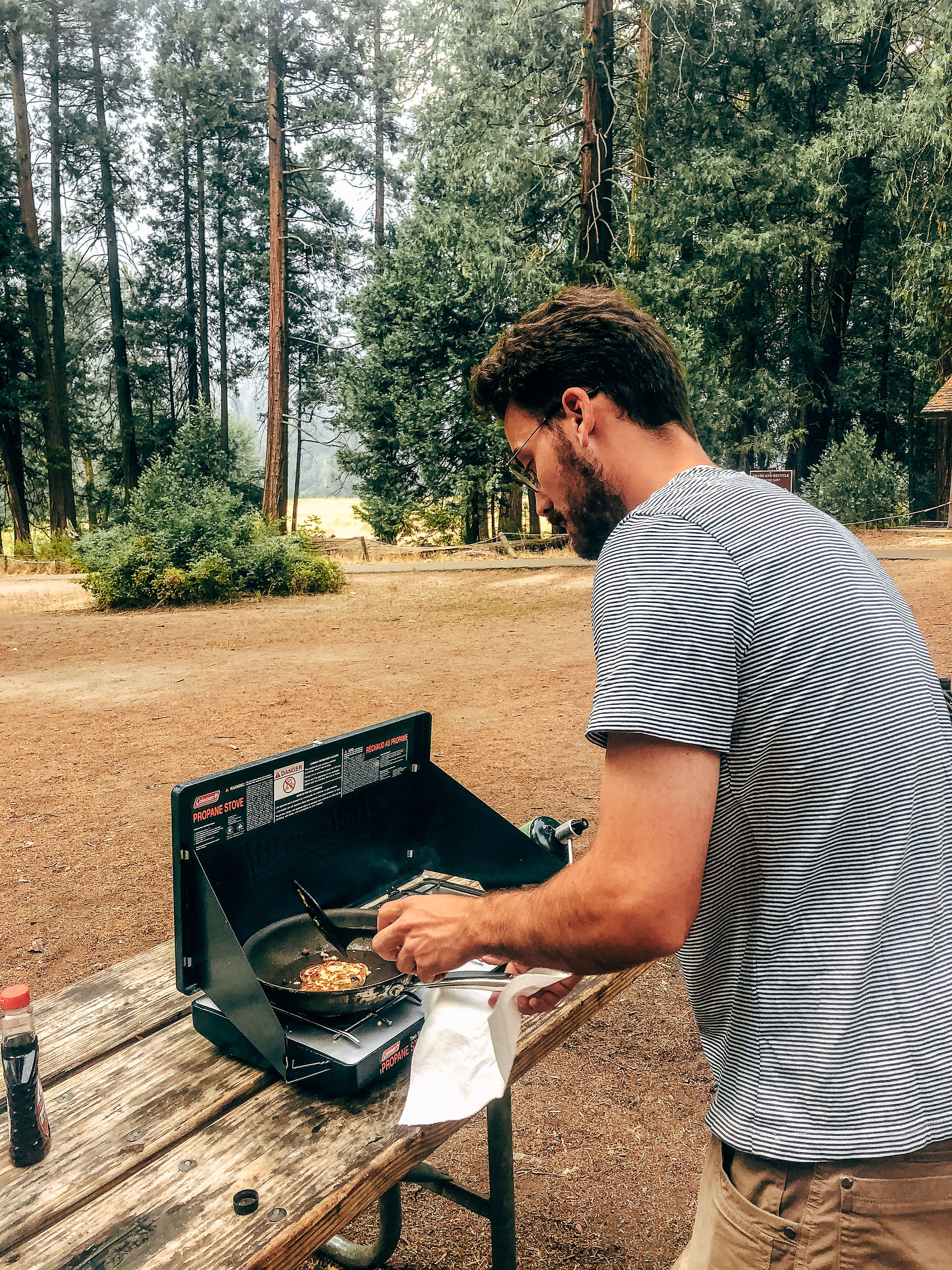 Man cooking with camping stove in woods