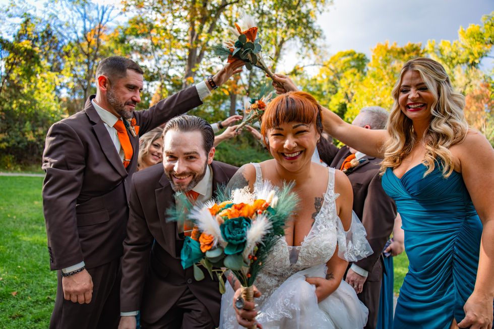 Bridal party making an arch while the married couple runs through with bouquet