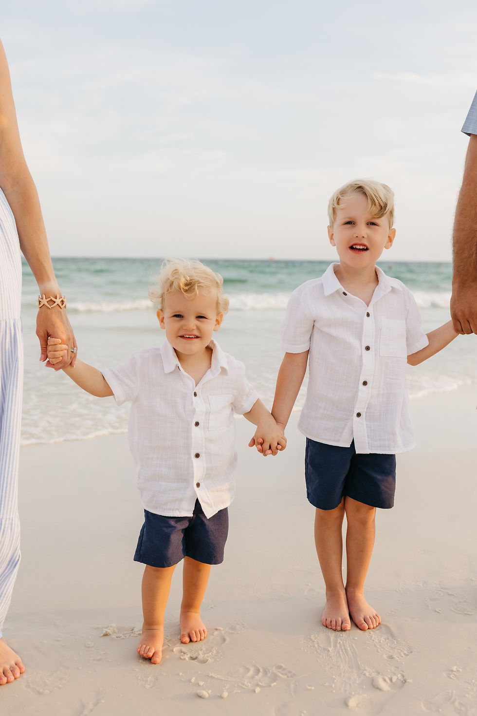 Two young boys holding their parents' hands during a family photography session, capturing the genuine connections and candid moments families can expect with Jessamine Marie Photography